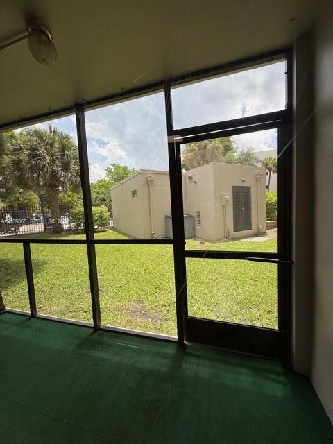 Screened-in enclosure featuring a metal-framed door, overhead light fixture, and green flooring Screened-in enclosure featuring a metal-framed door, overhead light fixture, and green flooring