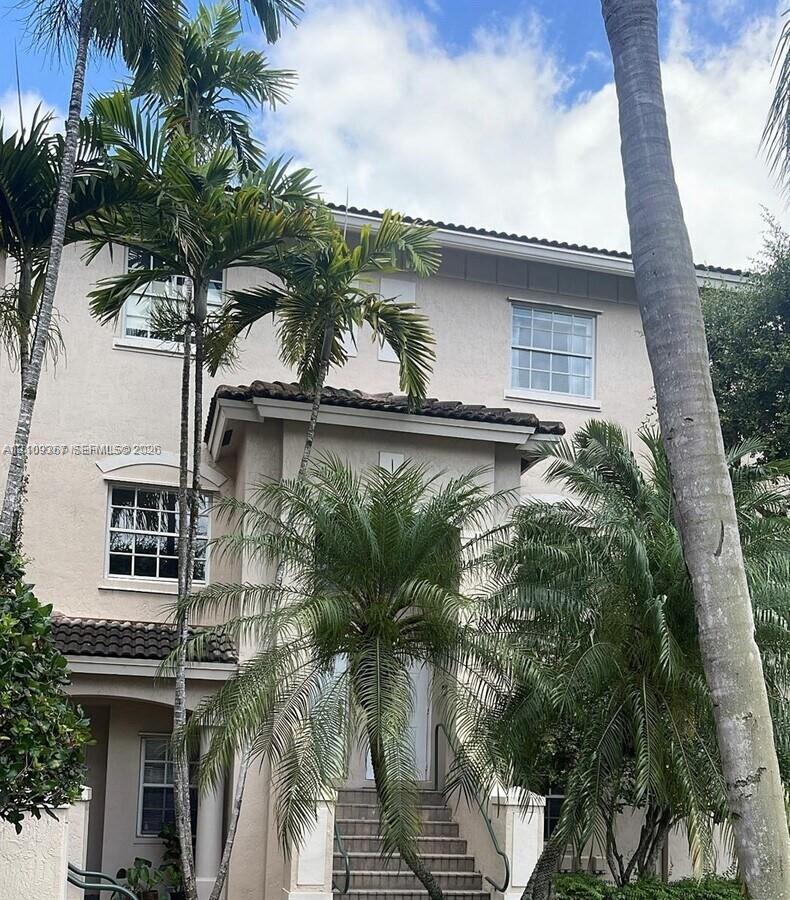 Multi-level exterior featuring a stucco facade, tiled roof, multi-pane windows, and concrete front steps with metal handrails