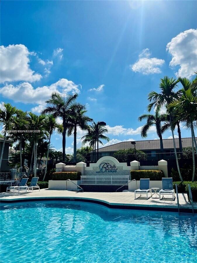 Swimming pool with light-toned deck surfacing and surrounding palm tree landscaping