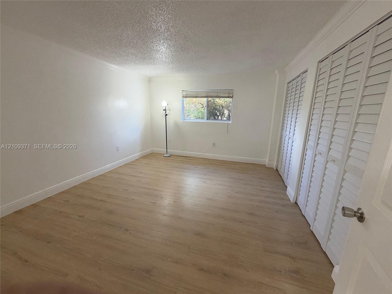 Room featuring wood-finish flooring, white walls, and two sets of louvered bi-fold closet doors