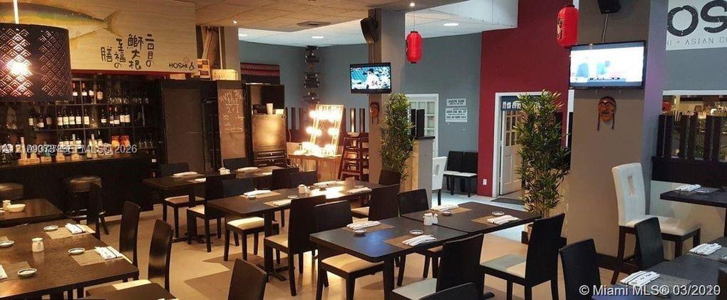 Commercial space featuring a dedicated bar area with built-in bottle shelving, recessed ceiling lighting, decorative pendant lighting, and multi-tone interior wall paint