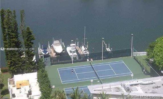 Tennis court featuring a hard surface, integrated lighting, and perimeter fencing, accompanied by a private boat dock with multiple slips
