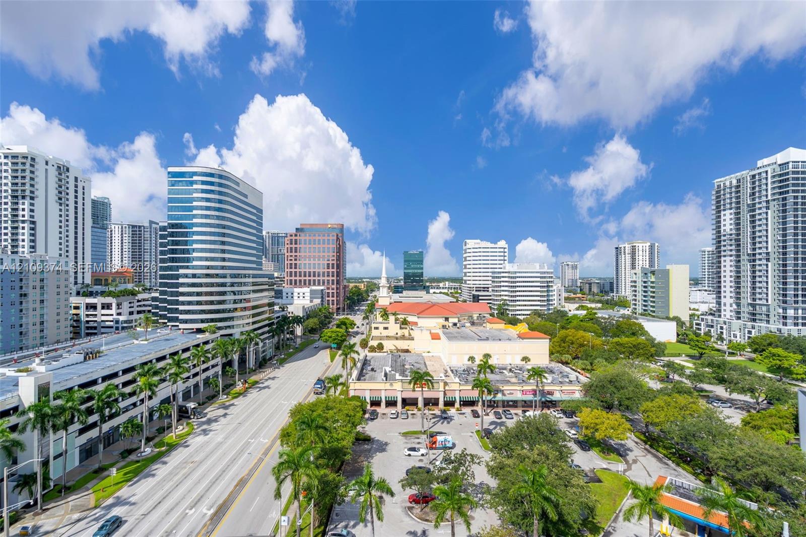 Aerial perspective of the urban landscape featuring high-rise architecture, prominent city thoroughfares, and lush palm tree landscaping