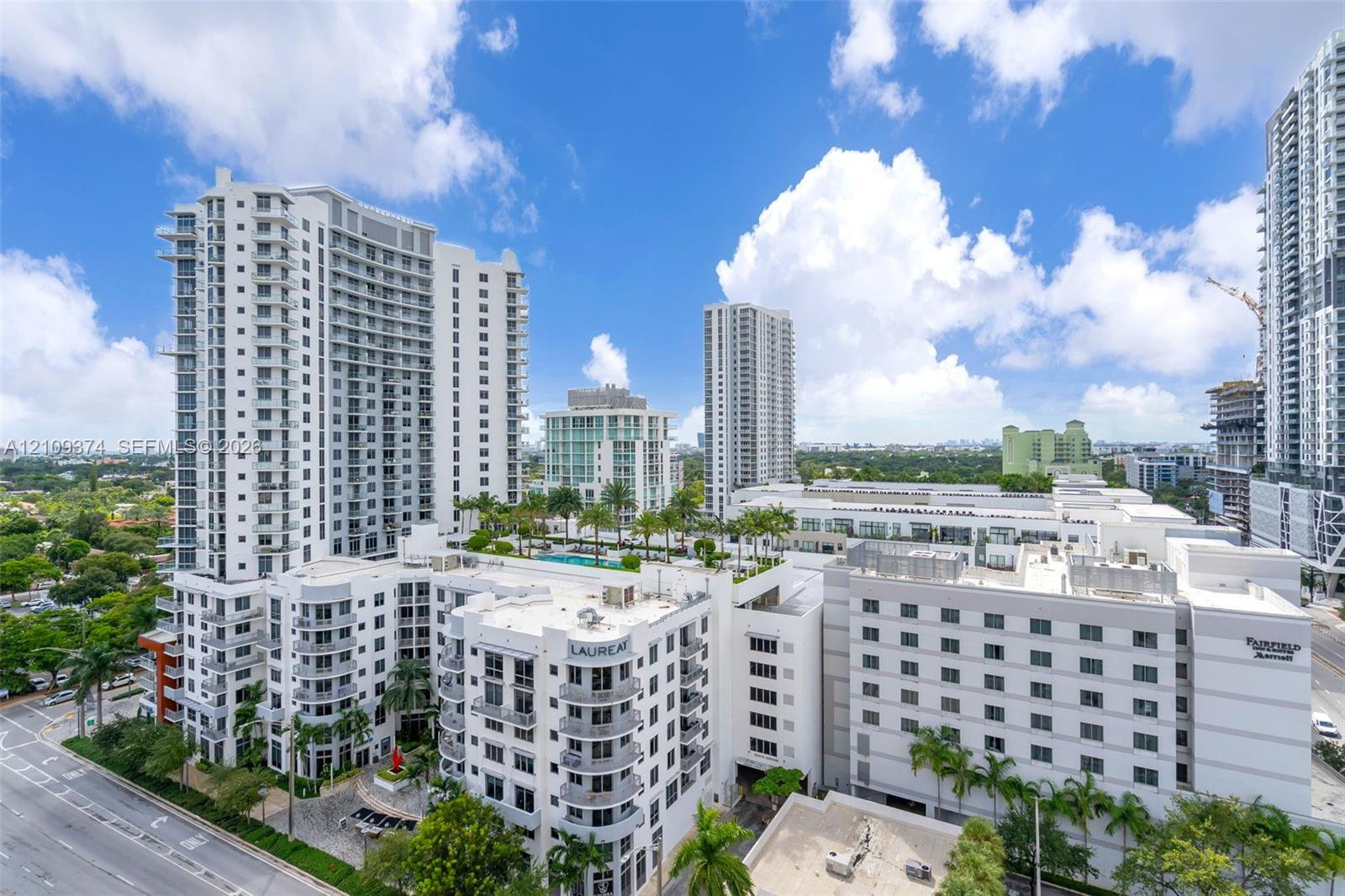 High-rise residential building featuring expansive glass balconies, a multi-level architectural design, and a rooftop terrace with a swimming pool