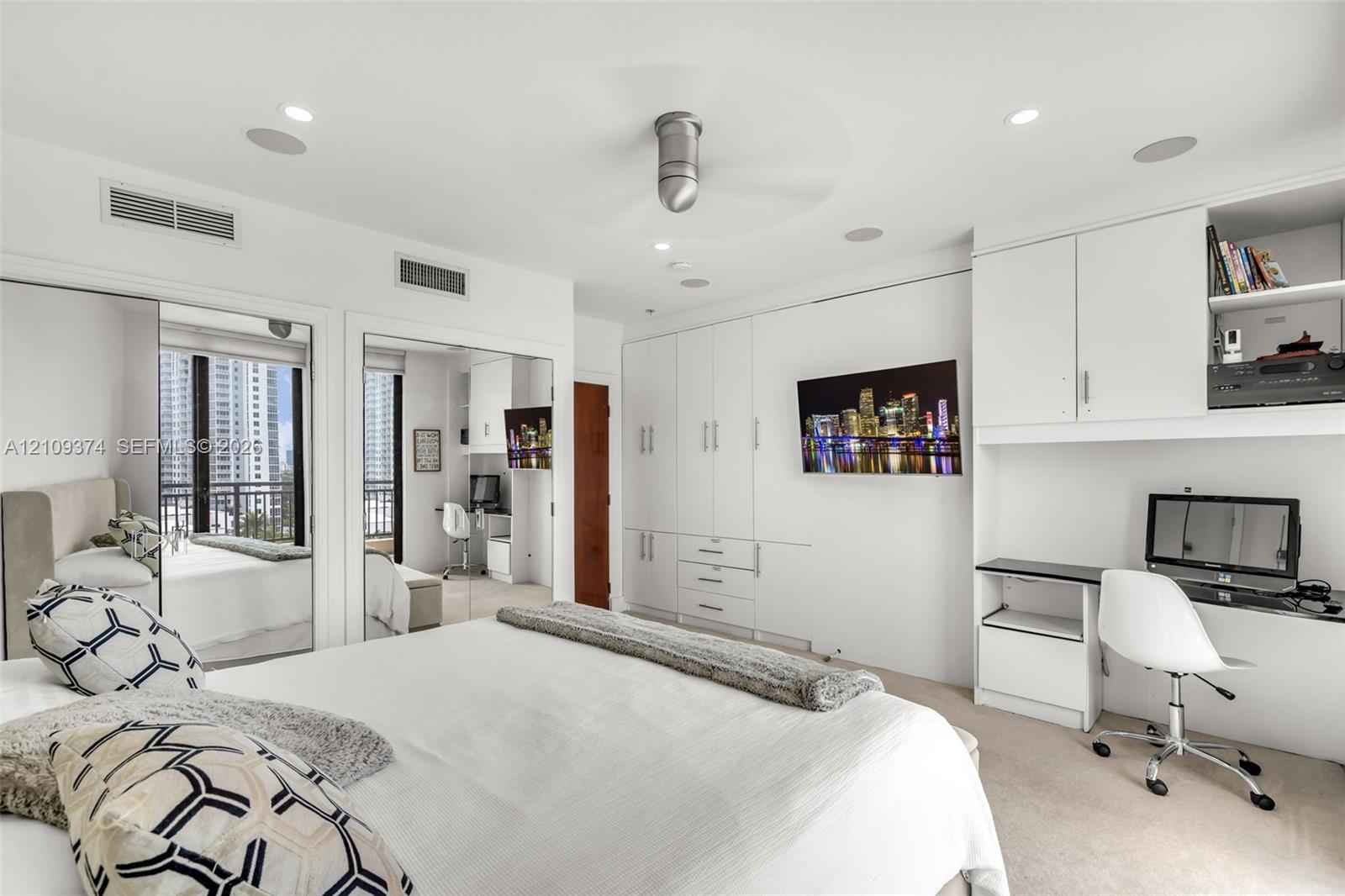Built-in floor-to-ceiling cabinetry, recessed lighting, integrated desk workspace, mirrored closet doors, and flush-mount ceiling fan