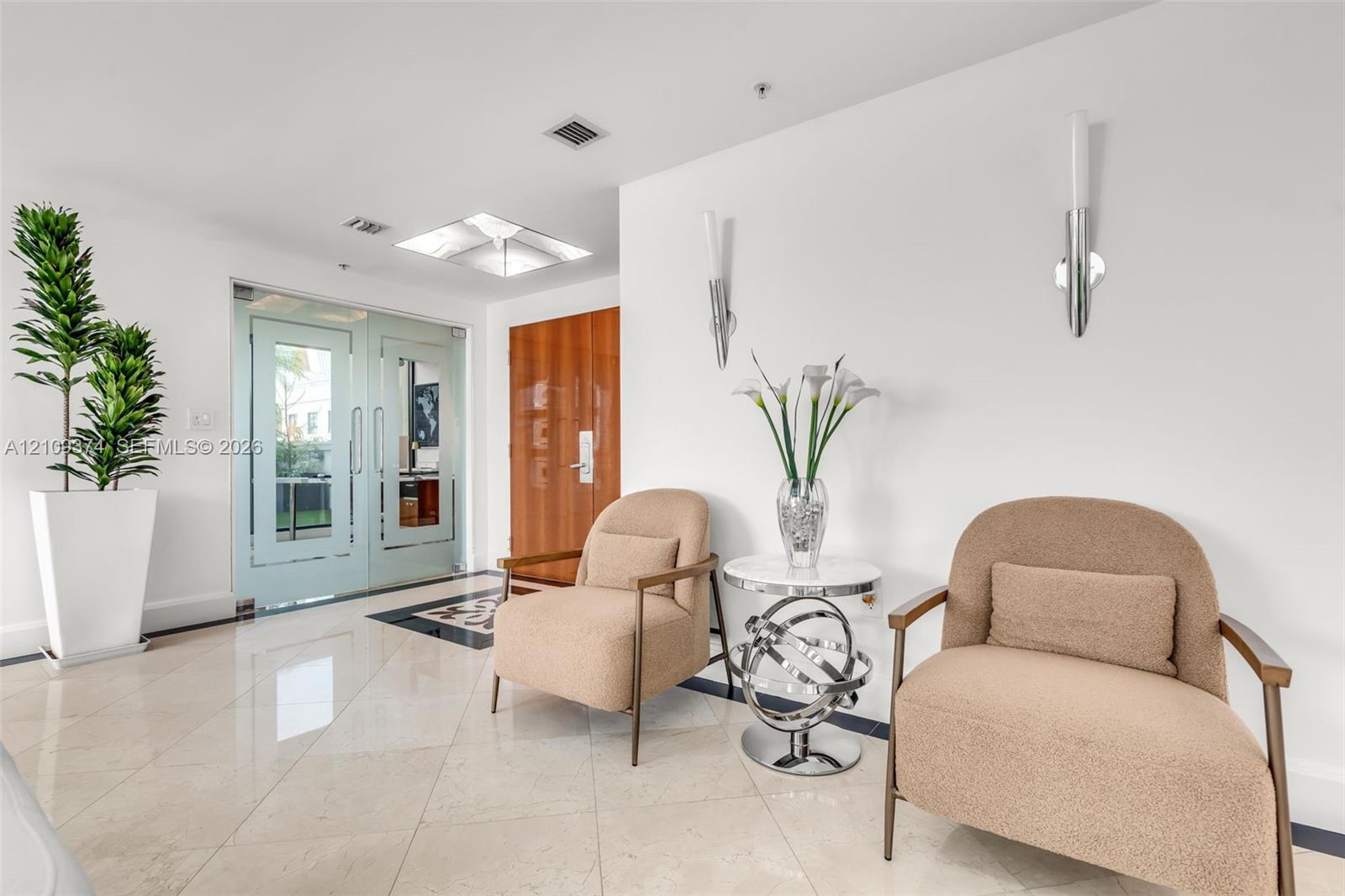 Polished stone flooring, dual glass-paneled entry doors, recessed ceiling lighting, and contemporary wall-mounted light fixtures