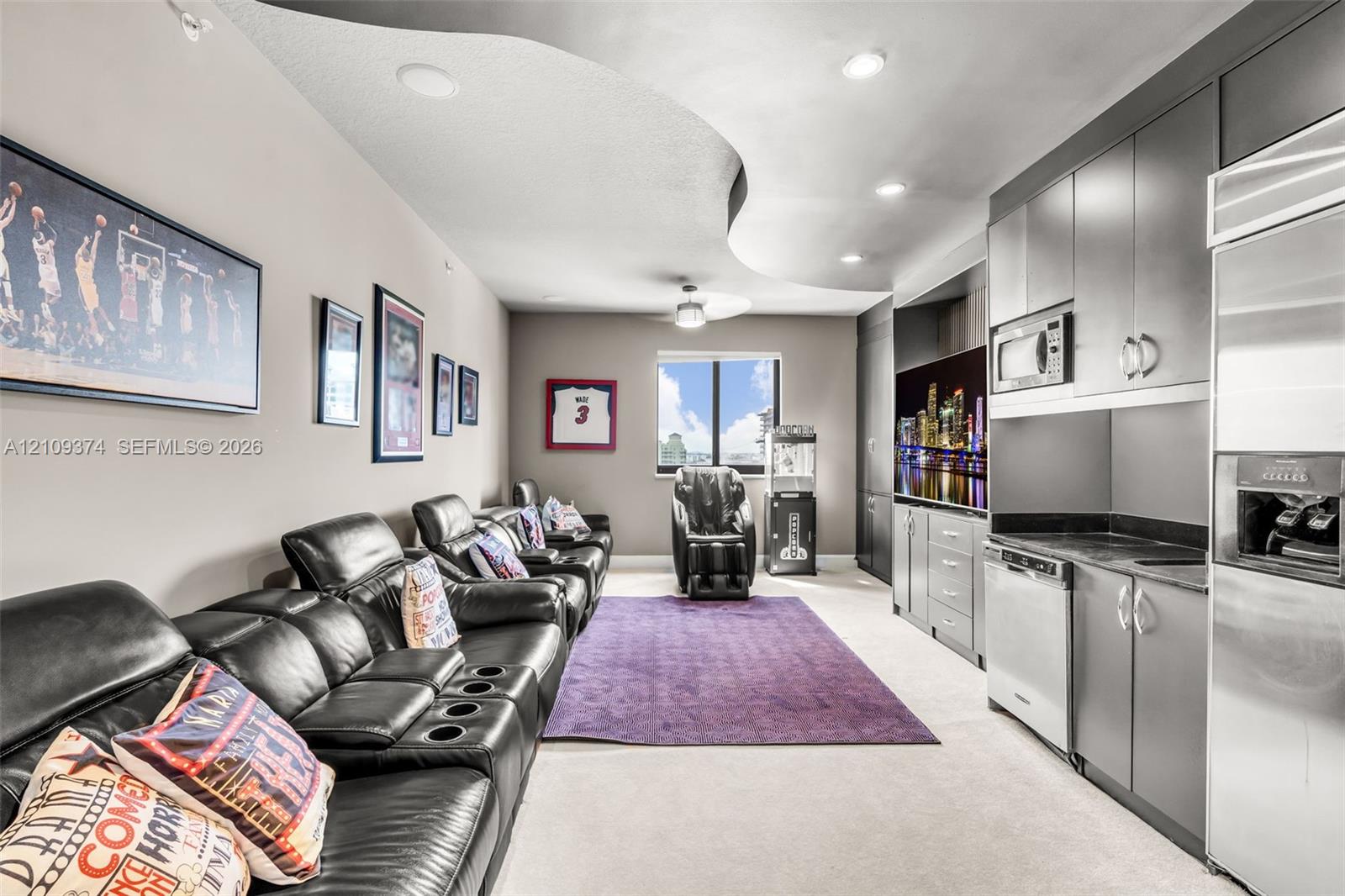 Curved architectural ceiling detail with recessed lighting, integrated cabinetry, stainless steel kitchen appliances, and neutral wall-to-wall carpeting