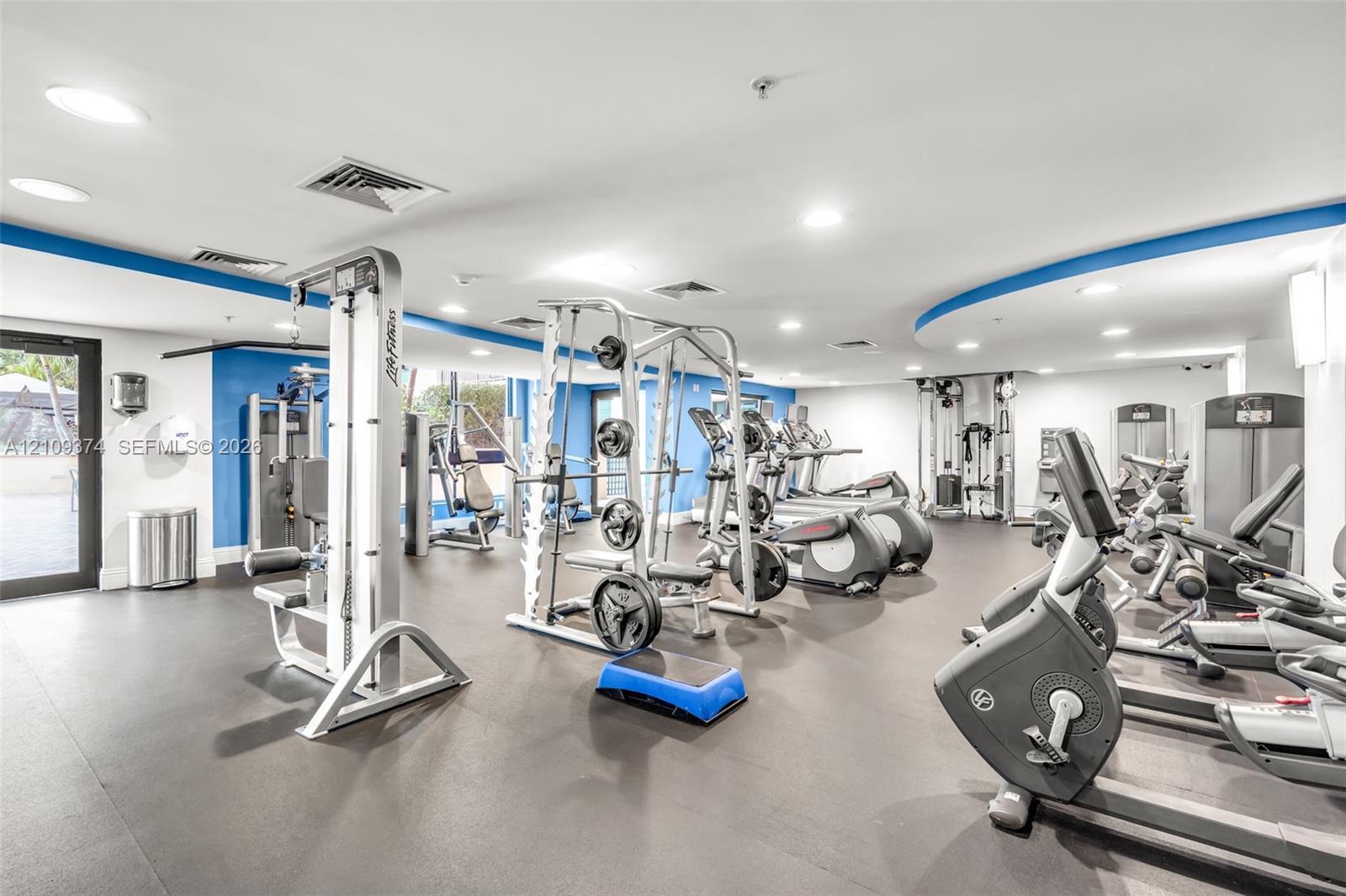 Fitness center featuring recessed lighting, rubberized flooring, and an assortment of strength training and cardiovascular equipment