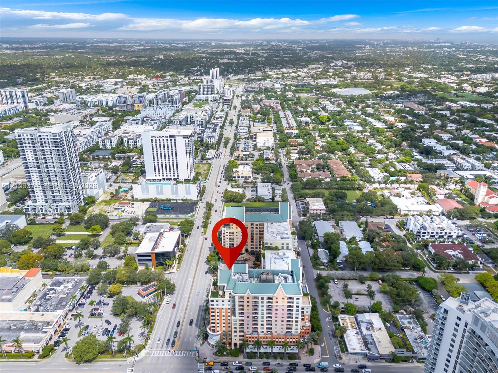 Aerial perspective of high-rise building featuring a multi-story exterior, ground-level parking, and prominent location within an established metropolitan grid