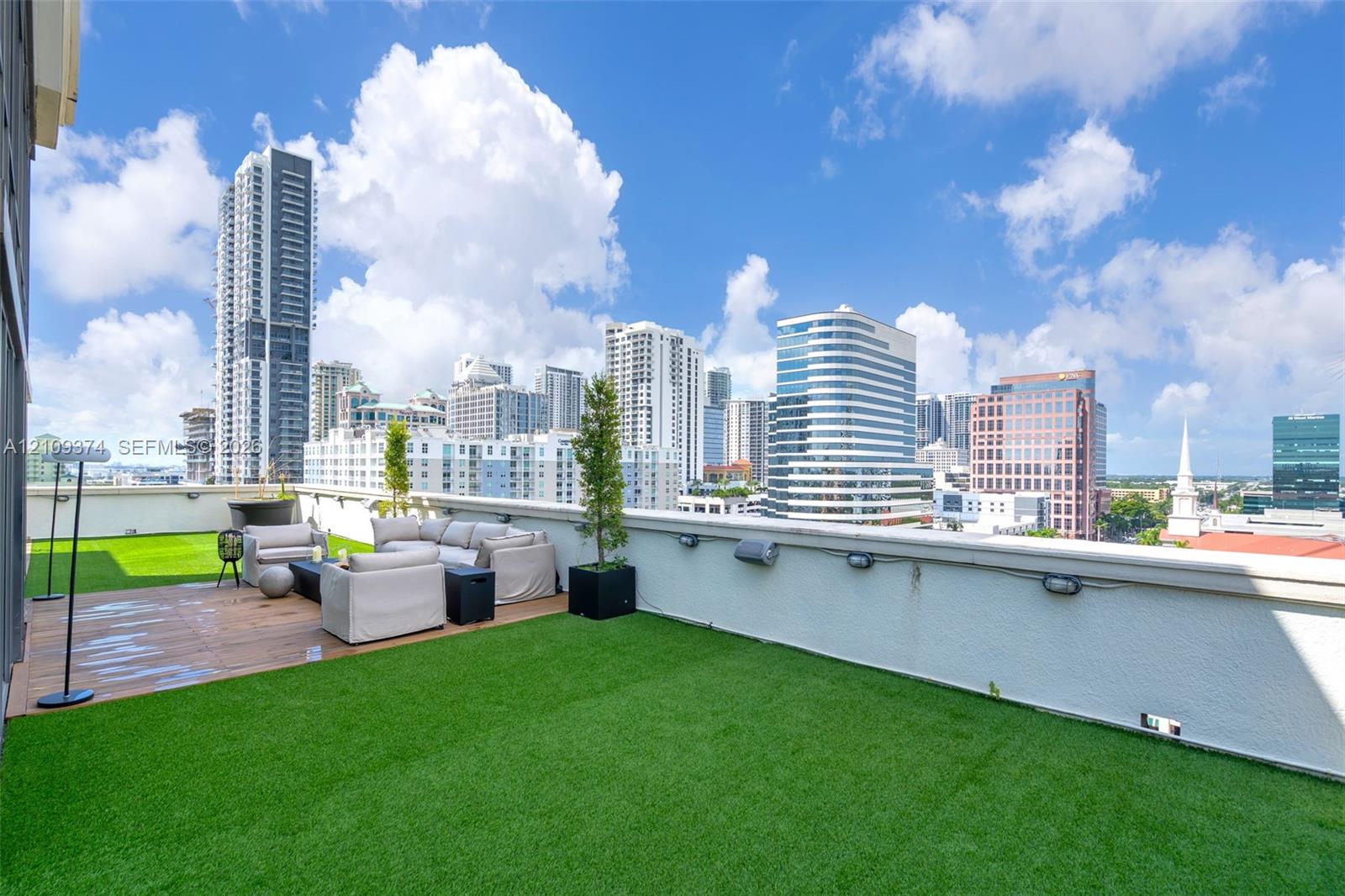 Rooftop terrace featuring synthetic turf, wood-finish decking, and perimeter wall-mounted lighting