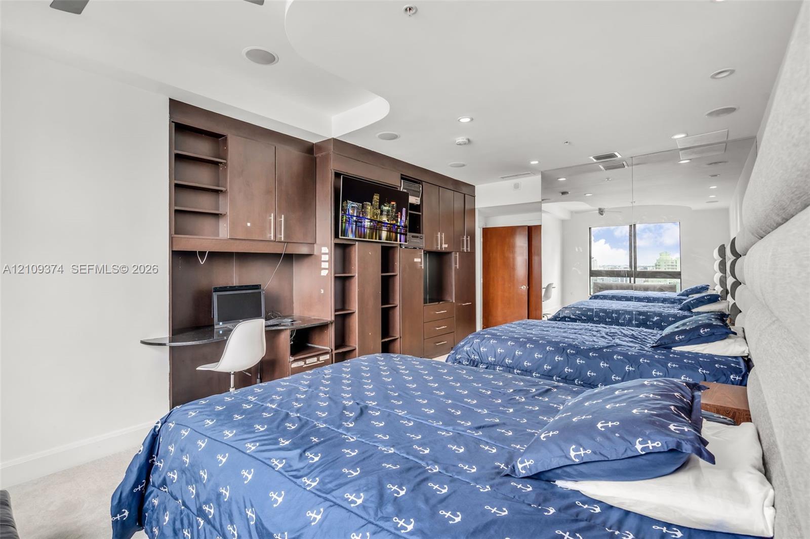 Custom built-in cabinetry with integrated desk station, recessed ceiling lighting, and large window
