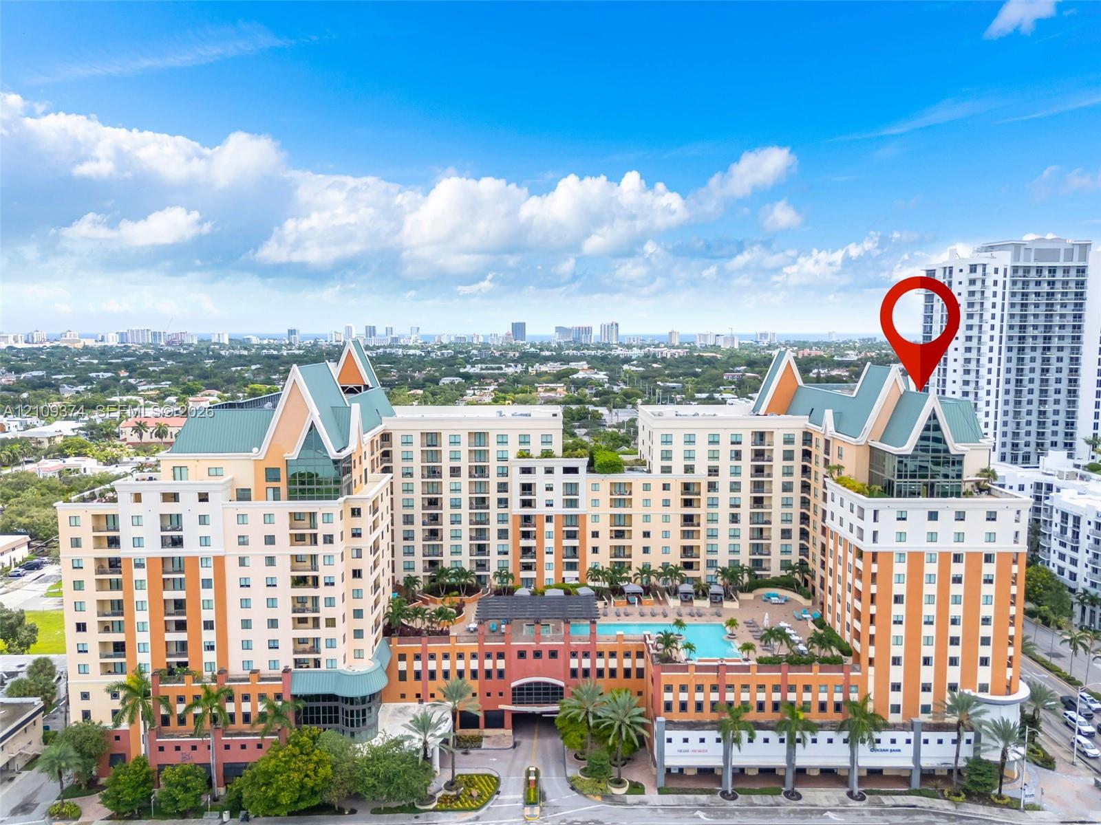 Multi-story residential complex featuring steep-pitched roof gables, stucco facade, integrated swimming pool, and lush perimeter landscaping