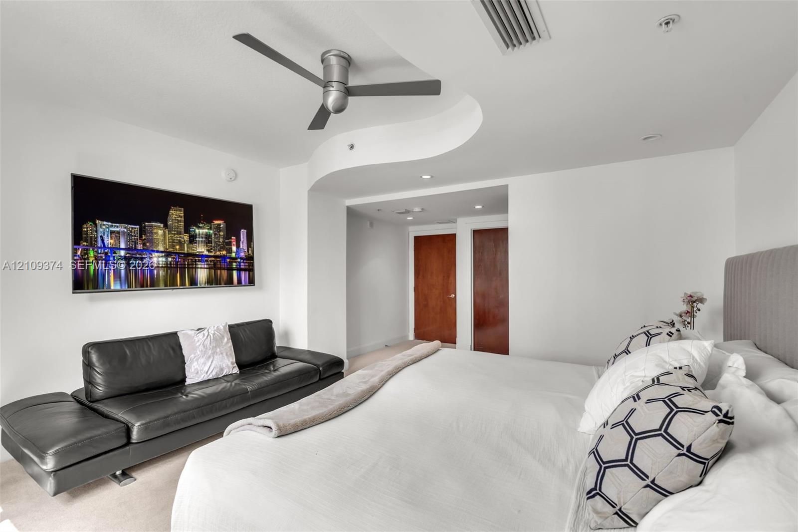 Curved architectural ceiling detail, dark-finish ceiling fan, recessed lighting, and solid-core wooden doors