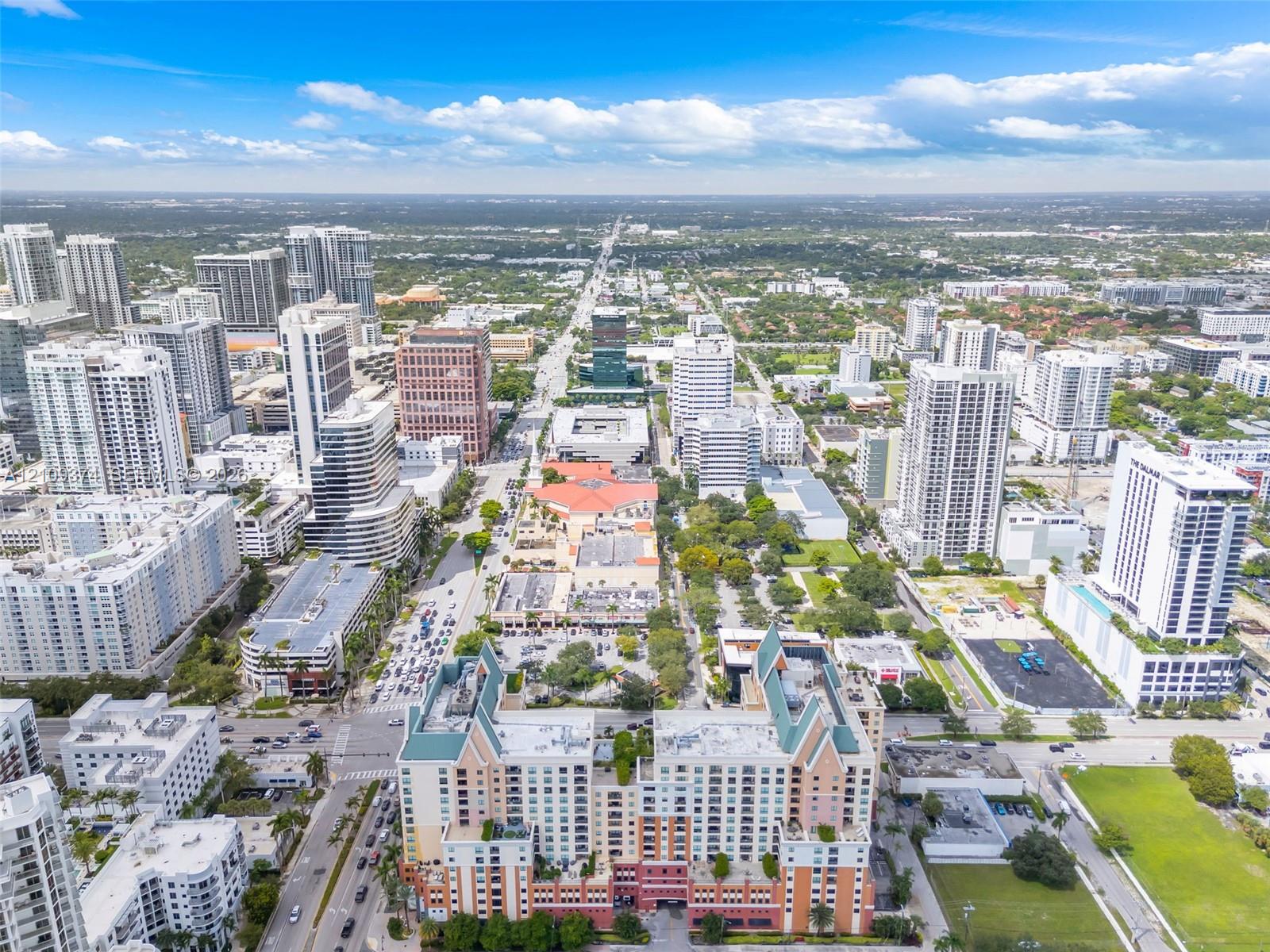 Aerial perspective of a high-rise urban center featuring multi-story residential buildings, commercial structures, structured parking facilities, and interconnected street networks