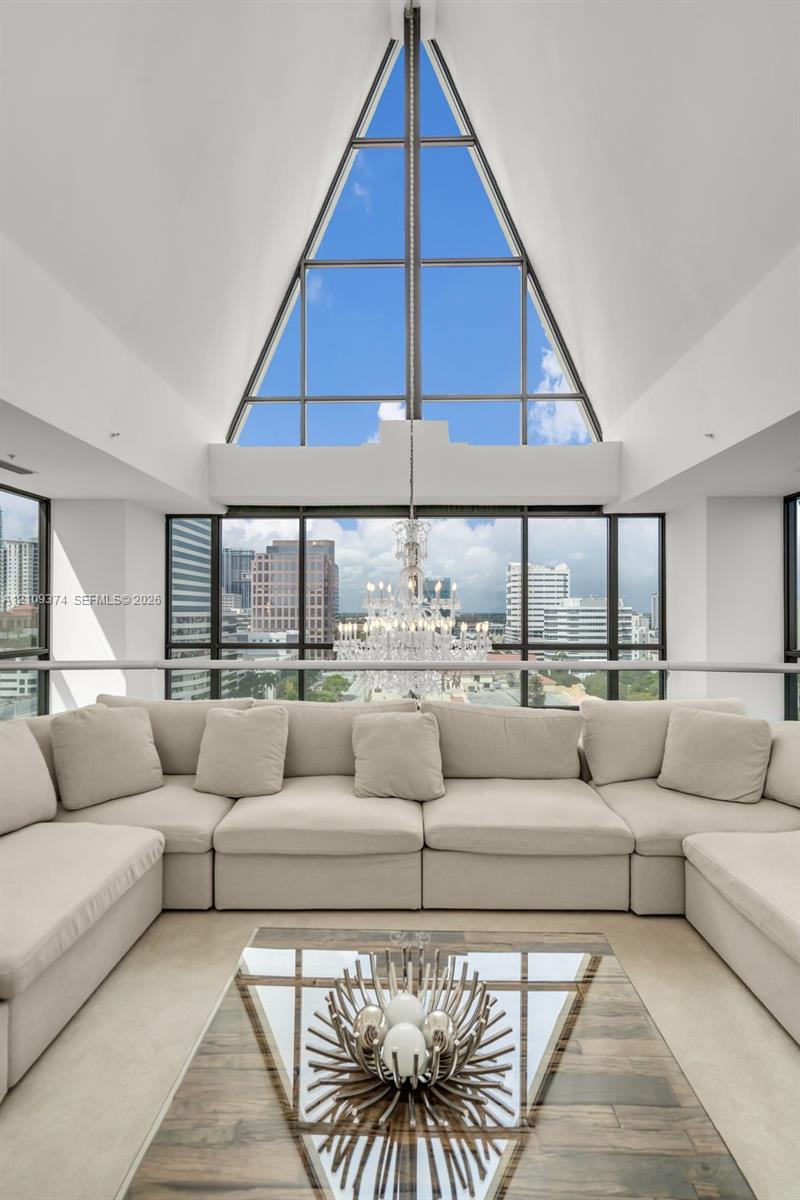 Vaulted A-frame ceiling with floor-to-ceiling triangular window, expansive glass window walls, and built-in crystal chandelier