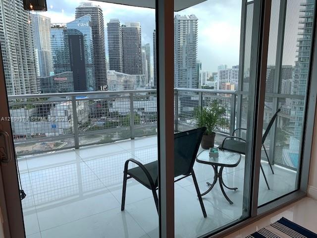Private balcony featuring expansive floor-to-ceiling glass sliding doors, polished tile flooring, and a metal railing system