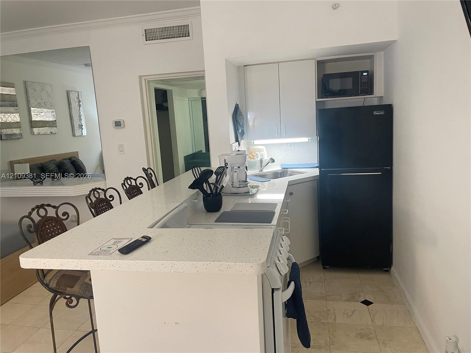 Neutral-tone floor tiles and built-in wet bar featuring a peninsula counter