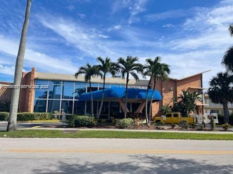 Expansive glass-paneled facade featuring brick exterior elements and a prominent blue covered entryway