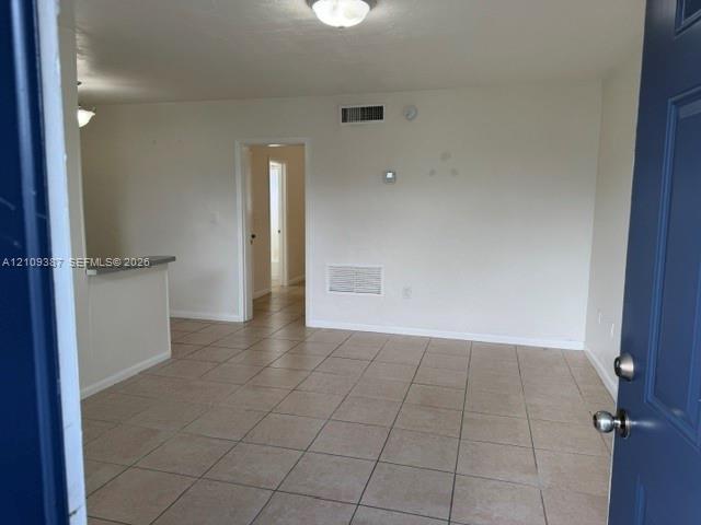 Interior space featuring neutral-toned tile flooring, recessed ceiling lighting, and a breakfast bar