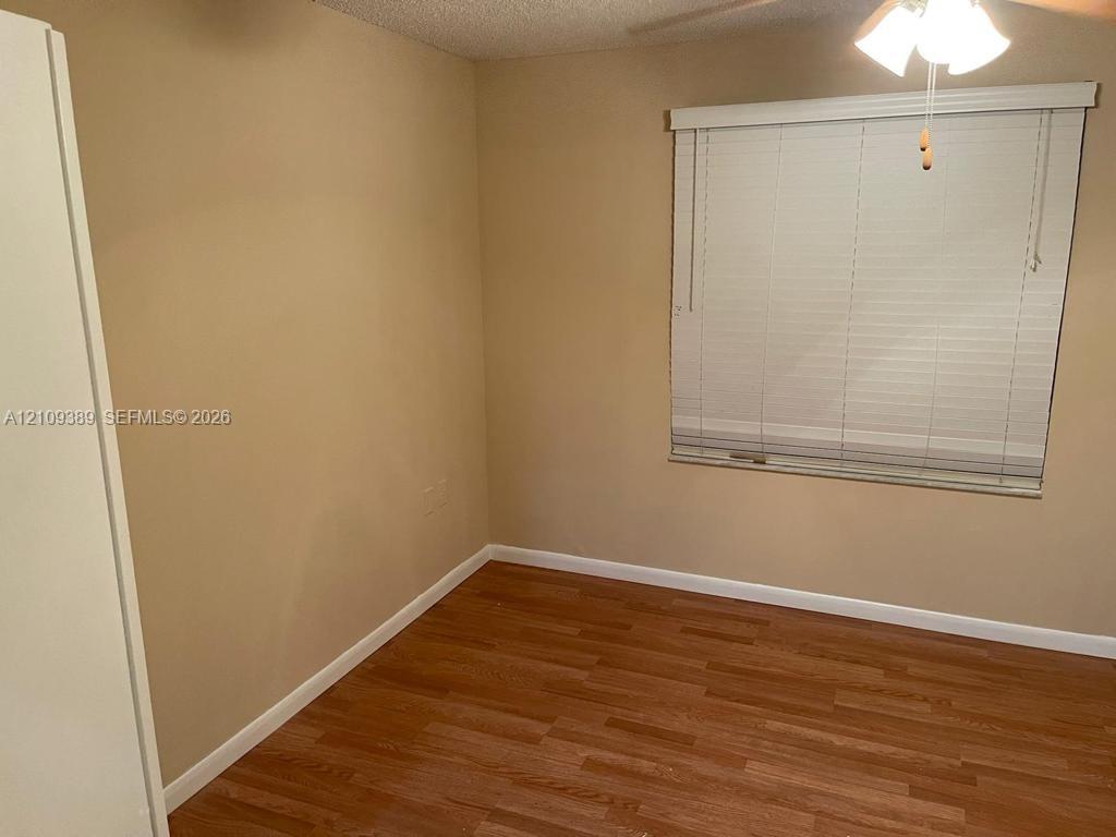 Wood-finish flooring, neutral wall tones, window with horizontal blinds, and a ceiling-mounted light fixture