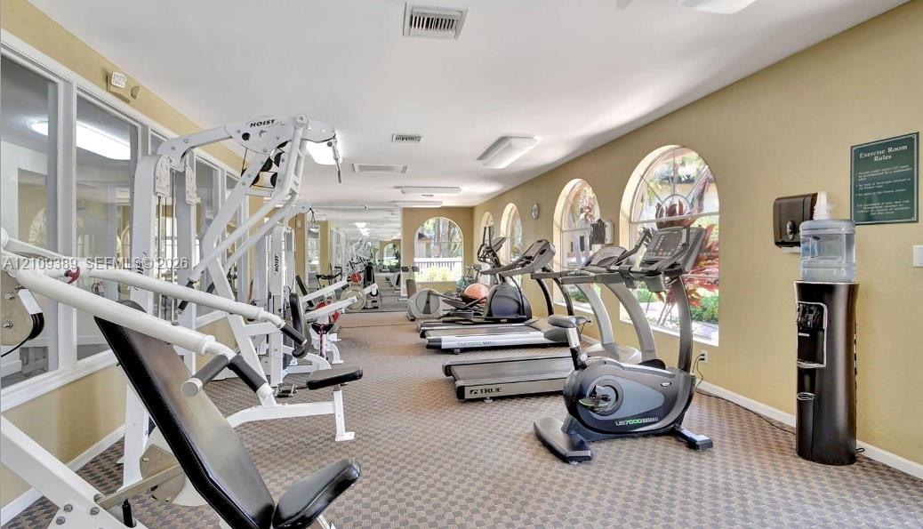 Fitness center featuring arched windows, wall-to-wall carpeting, and recessed ceiling lighting