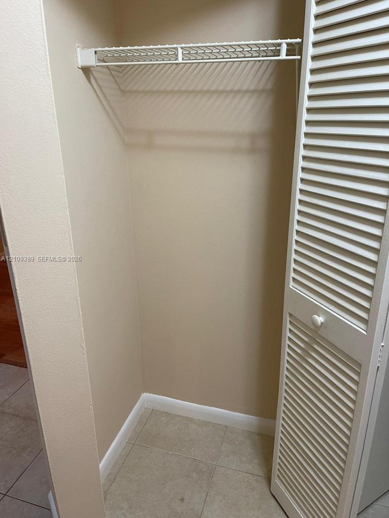 Reach-in closet featuring white louvered bi-fold doors and a built-in wire storage shelf