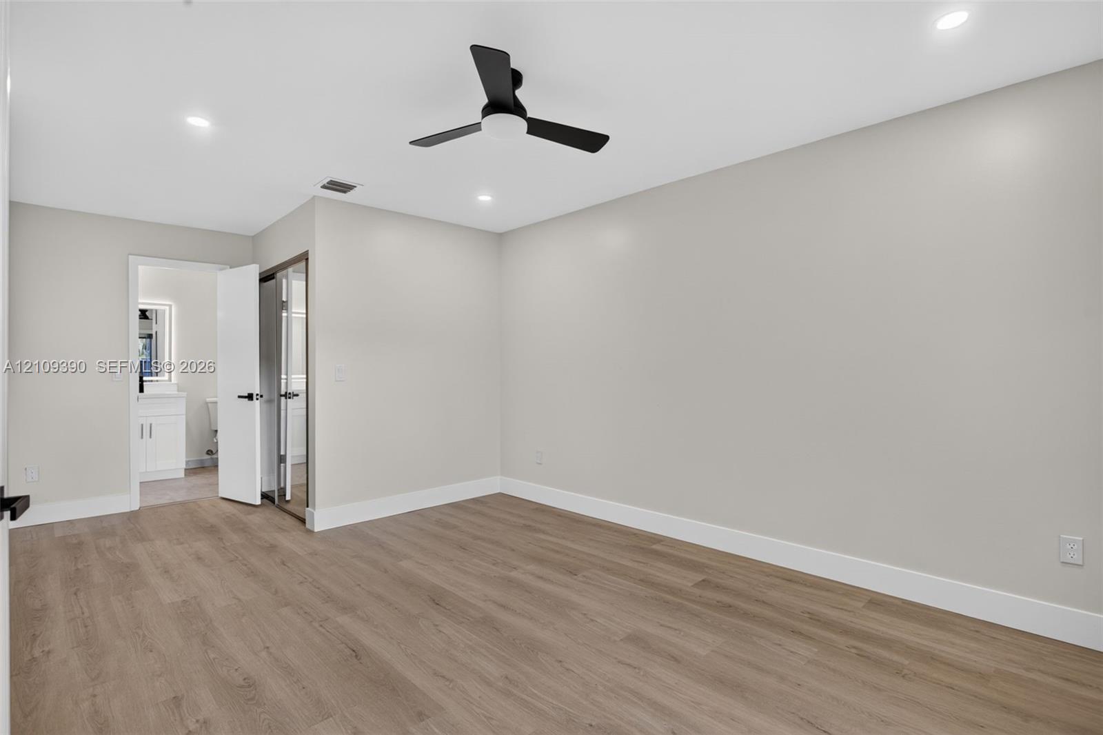 Neutral-toned interior featuring wood-finish flooring, recessed lighting, and a matte black ceiling fan