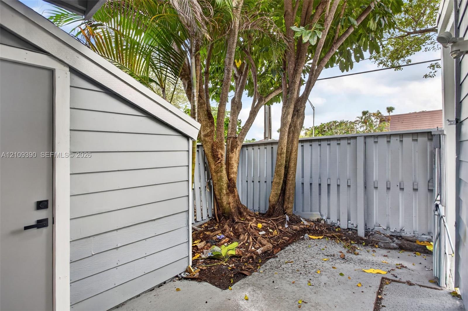 Exterior utility space featuring horizontal lap siding, concrete flooring, and a privacy-style fenced enclosure