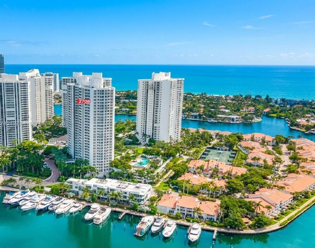 Aerial coastal perspective featuring high-rise towers, private marina slips, and proximity to the open ocean