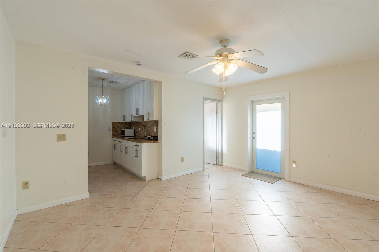 Tile flooring, ceiling-mounted light fixture with a fan, and white cabinetry featuring stone-surface countertops Tile flooring, ceiling-mounted light fixture with a fan, and white cabinetry featuring stone-surface countertops