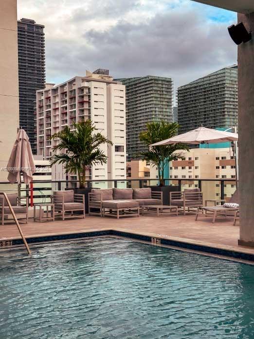 Rooftop swimming pool with tile-accented edge, paved deck, integrated planters, and metal railing