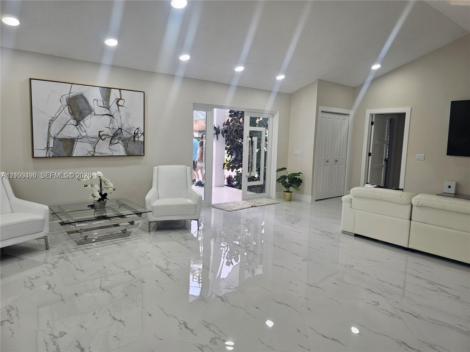 Vaulted ceilings, large-format stone-finish flooring, recessed lighting, and a glass-panel entry door