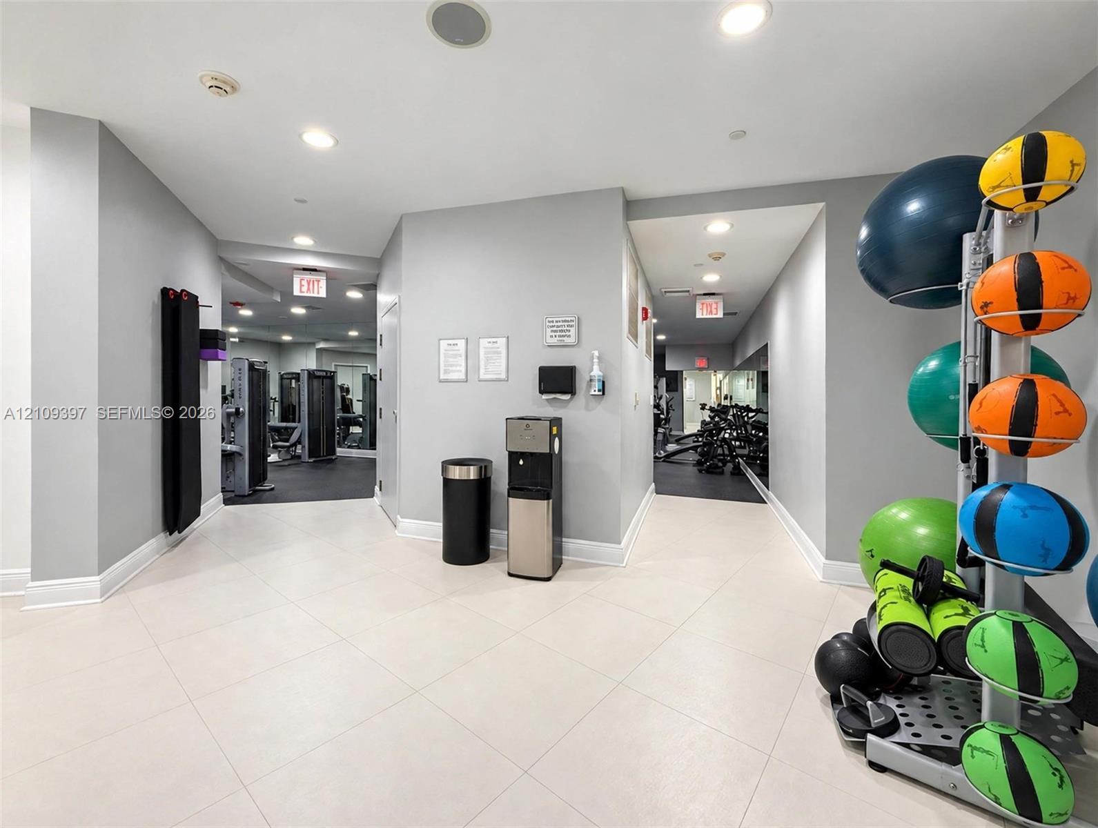 Fitness center featuring recessed lighting, tiled flooring, built-in mirrored wall surfaces, and partitioned exercise zones