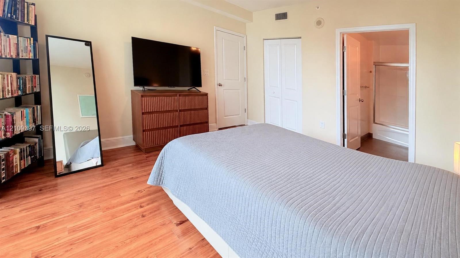 Room featuring wood-finish flooring, two-panel interior doors, and dual-door reach-in closet