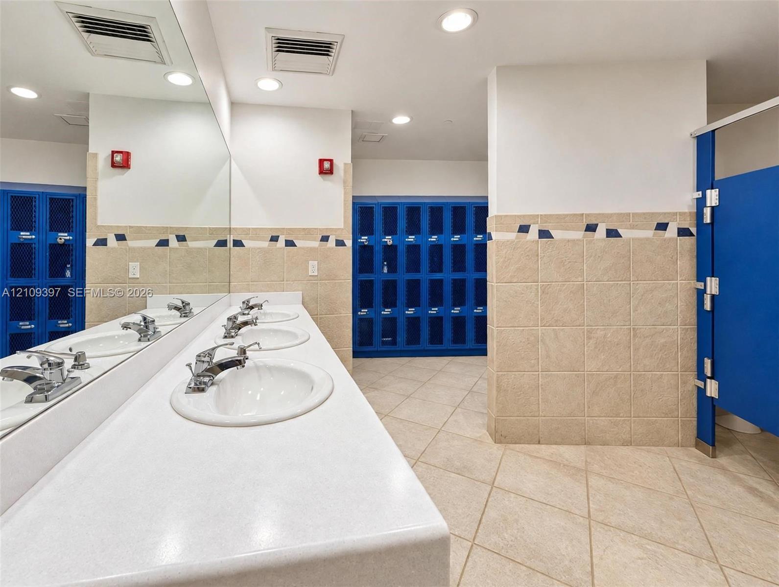 Multi-station vanity featuring white composite countertops, integrated oval sinks, chrome-finish faucets, and a full-width wall mirror