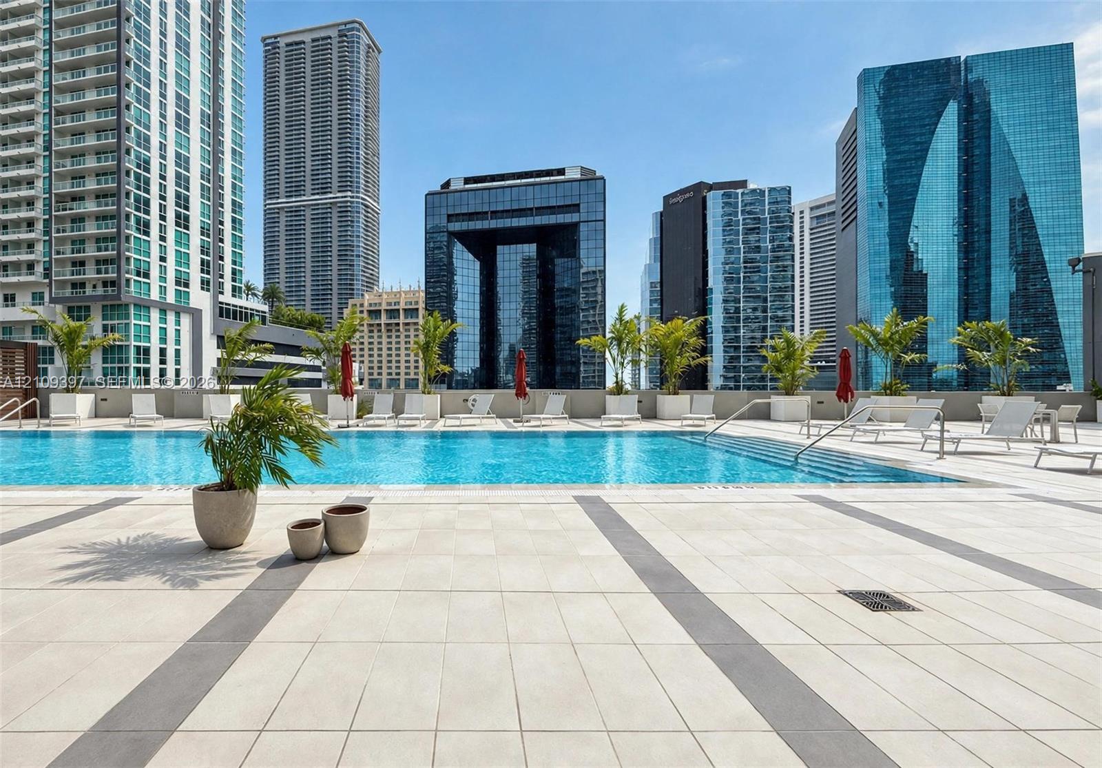 Outdoor swimming pool featuring a tiled deck, stepped entry, and built-in landscape planters against a metropolitan skyline backdrop
