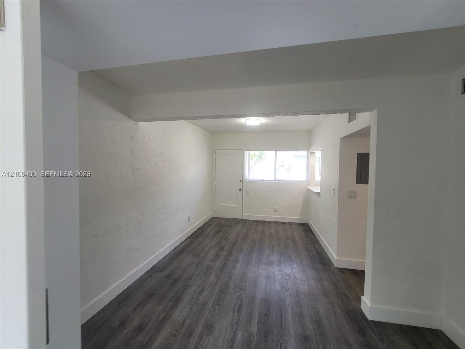 Interior space featuring wood-finish flooring, white textured walls, and a multi-panel exterior door