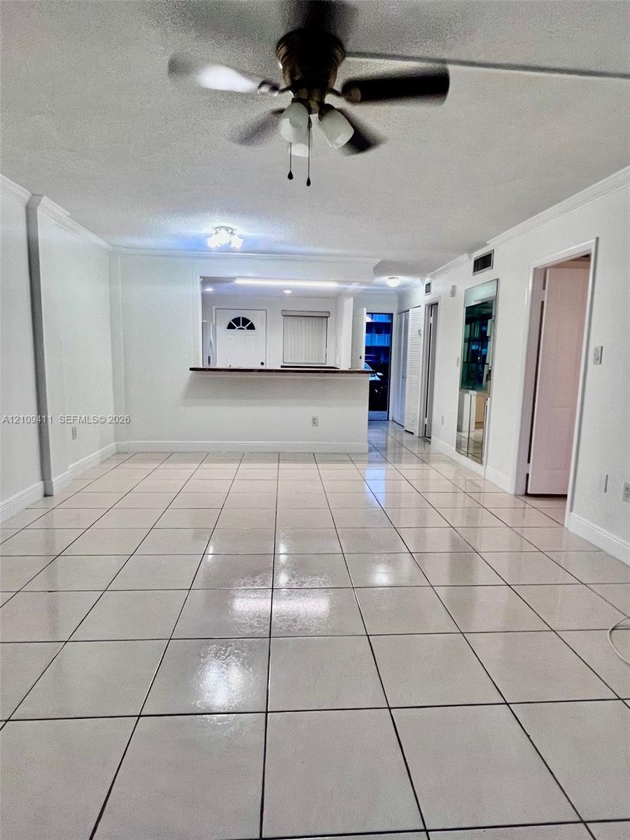 Interior space featuring large-format ceramic tile flooring, a pass-through service counter, and a ceiling fan with integrated lighting