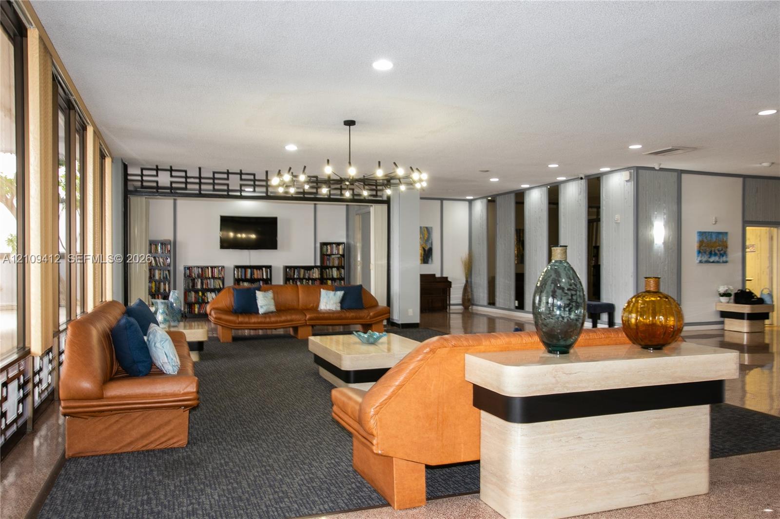 Spacious common area featuring recessed lighting, a statement chandelier, expansive floor-to-ceiling windows, and decorative room dividers