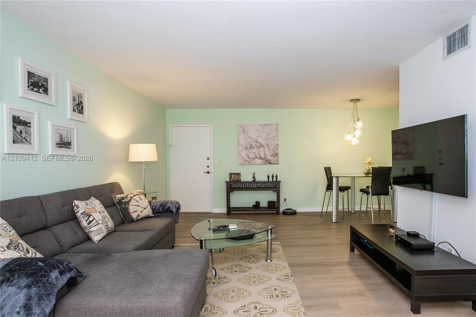 Open-concept interior featuring wood-finish flooring and a multi-pendant light fixture