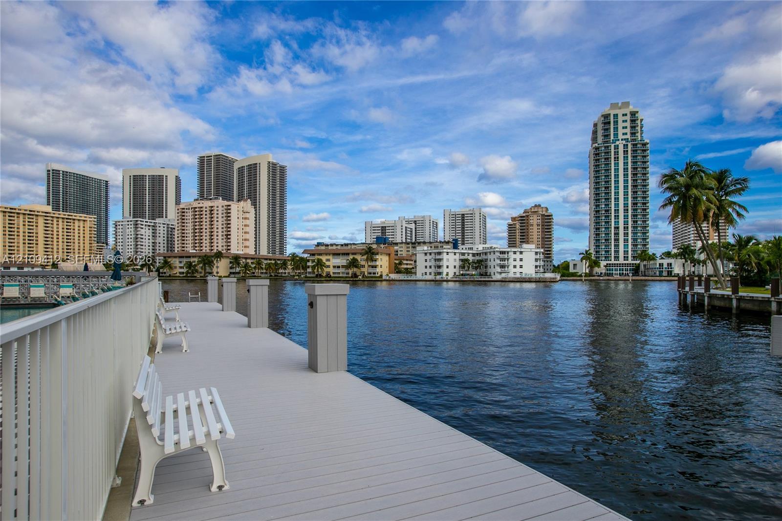 Waterfront dock featuring composite decking, white railings, and built-in benches