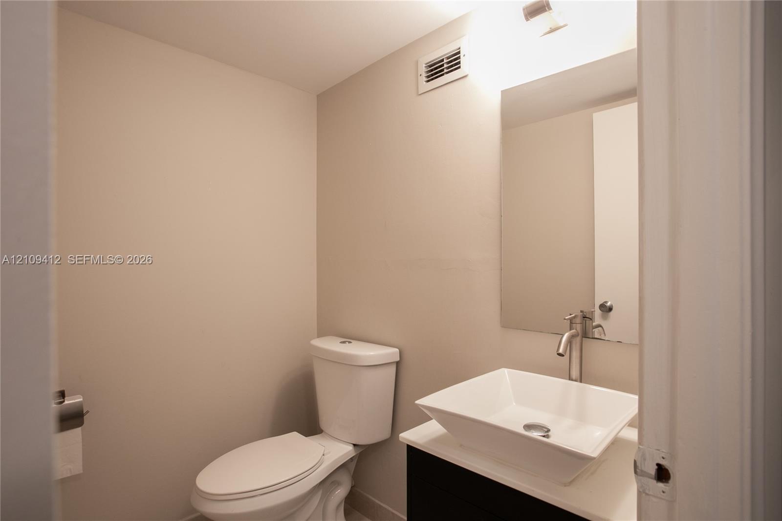 Modern vanity featuring a rectangular vessel sink with a wall-mounted faucet, crisp countertop, and frameless mirror