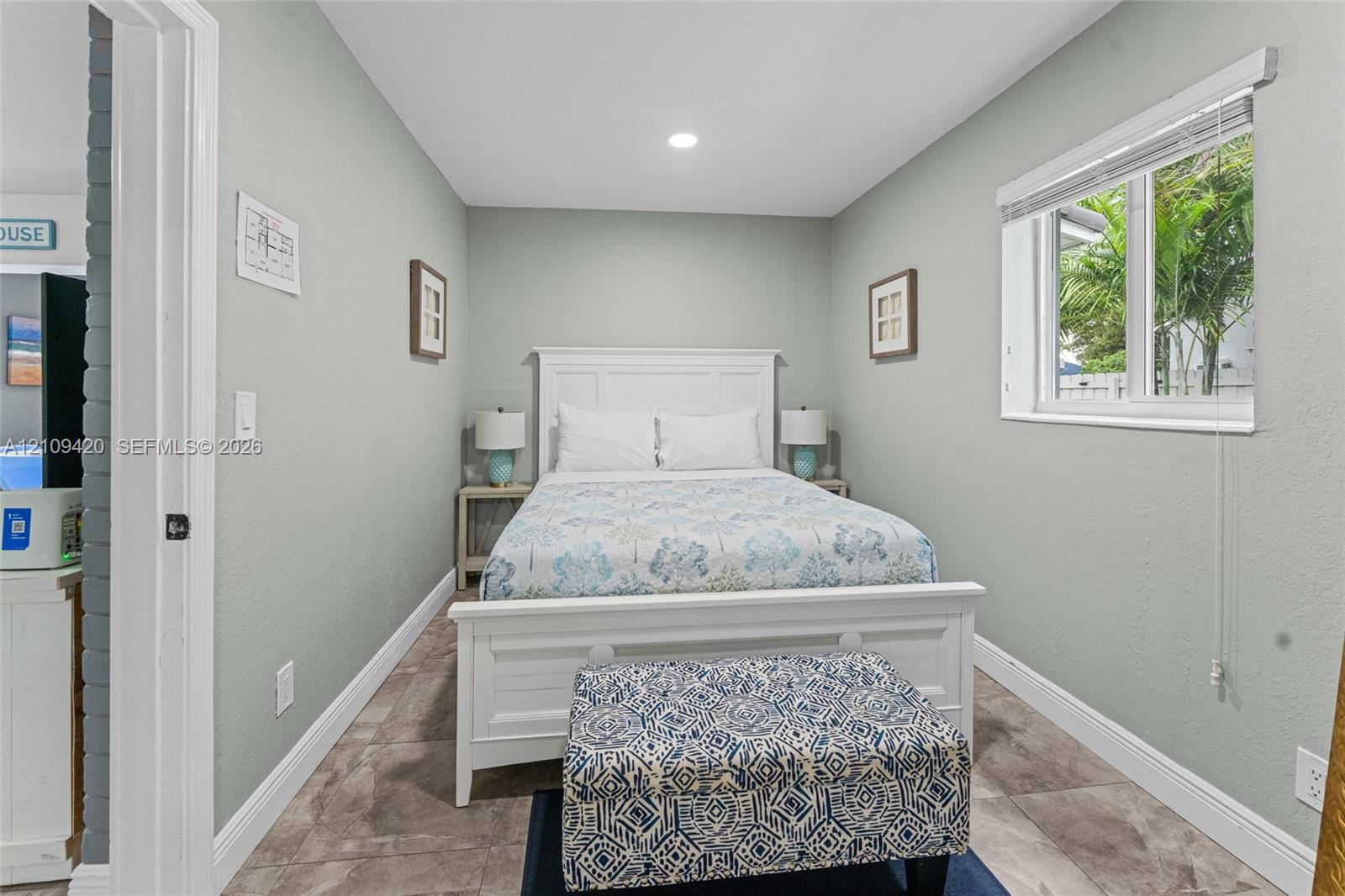 Neutral wall-toned room featuring stone-finish floor tiling and a single-pane sliding window
