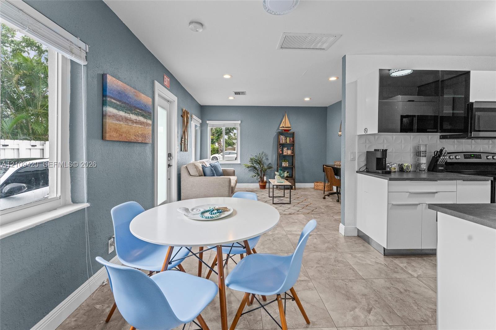 Kitchen featuring white cabinetry, dark countertops, a textured tile backsplash, and tile flooring, enhanced by recessed lighting