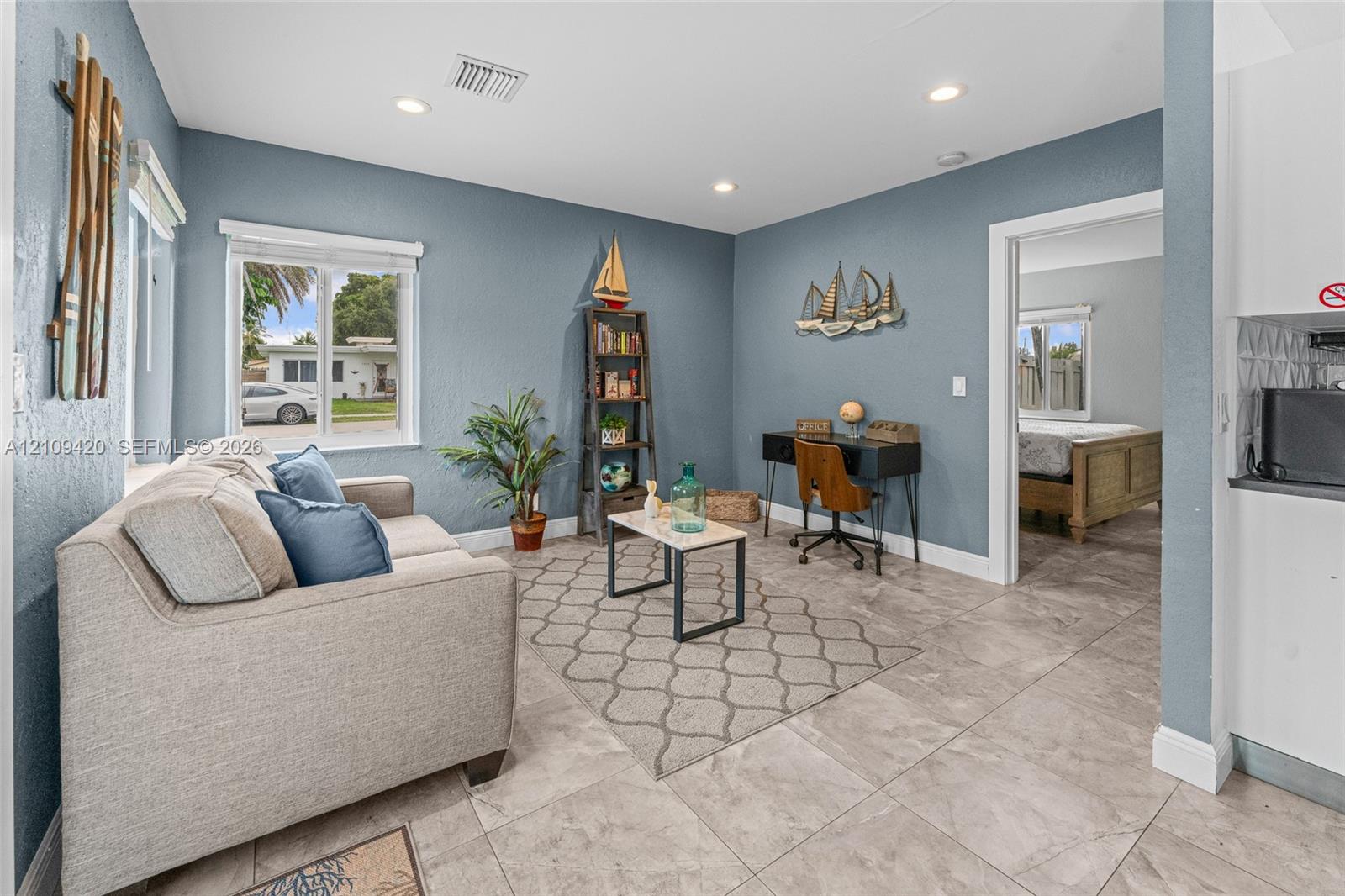 Living area featuring neutral-toned tile flooring, recessed lighting, and a window providing natural light
