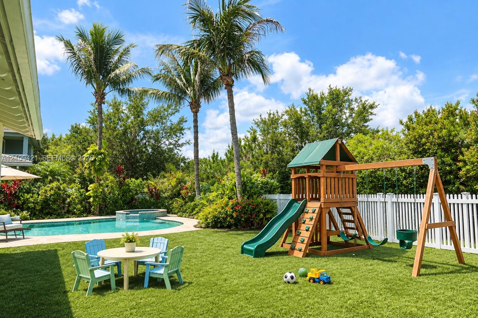 Backyard featuring a swimming pool, integrated spa, perimeter vinyl fencing, and mature palm trees
