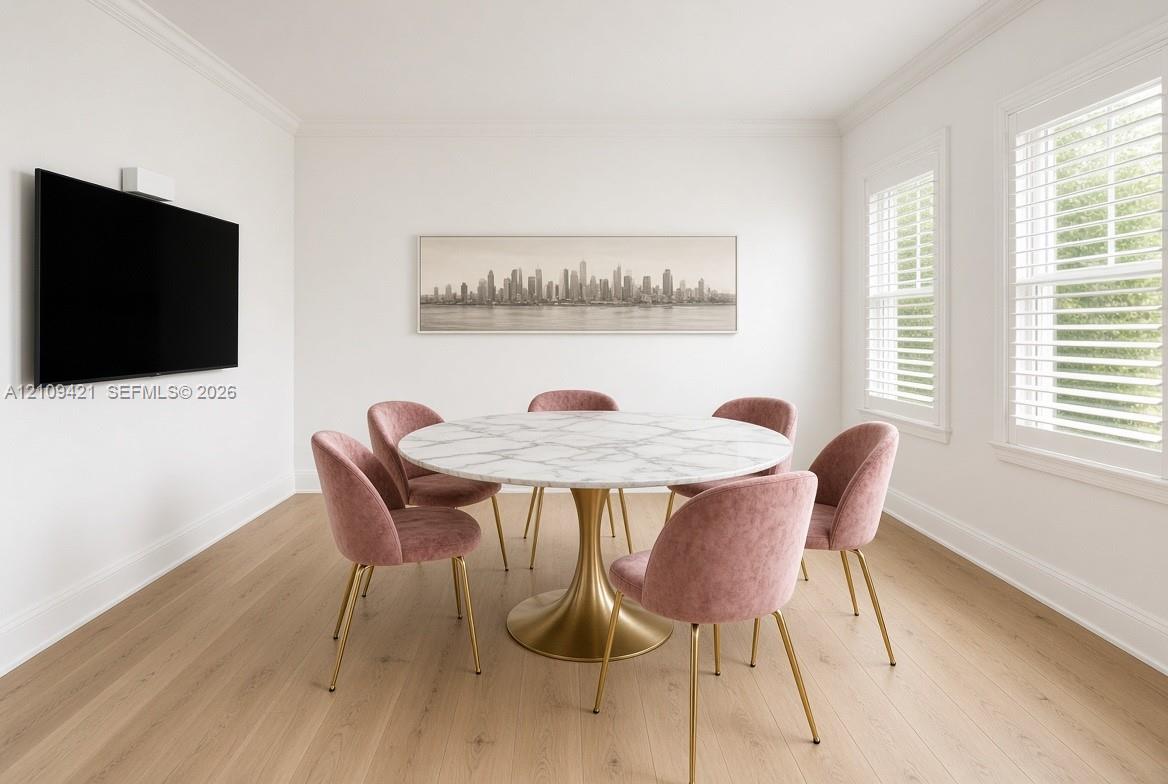 Bright room featuring wood-finish flooring, dual windows with plantation shutters, and crown molding