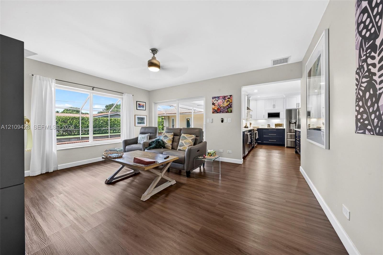 Open-concept living space featuring wood-finish flooring, a ceiling fan, and expansive windows