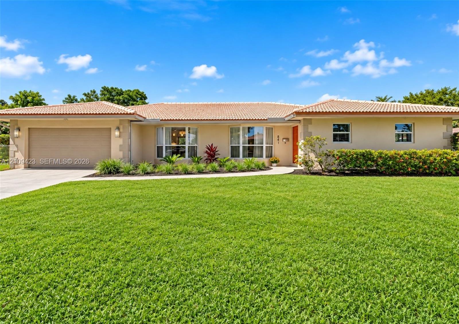Single-story residence featuring a tile roof, stucco exterior, two-car garage, and manicured landscaping