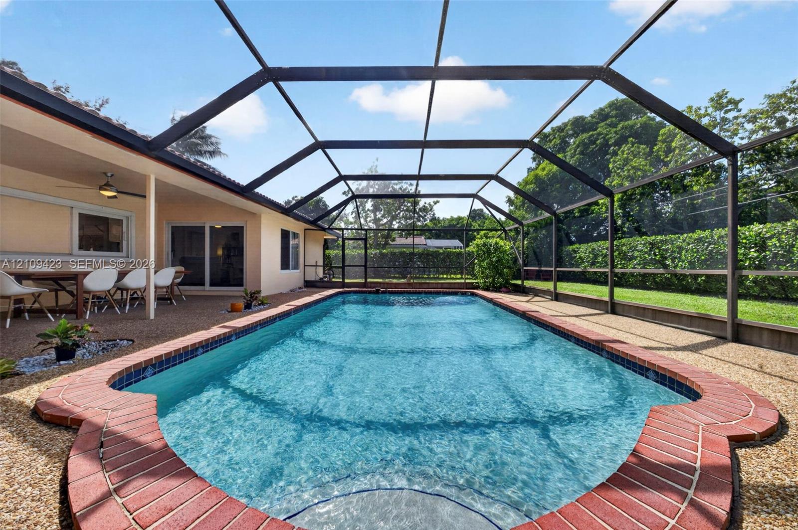 Screened lanai featuring a swimming pool with red brick coping, aggregate patio flooring, and a metal enclosure